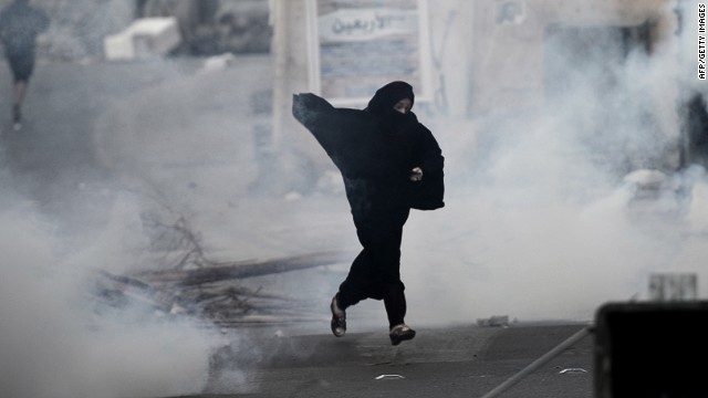 A protester runs from tear gas fired by Bahrain&#39;s riot police during a protest west of Manama on December 17.