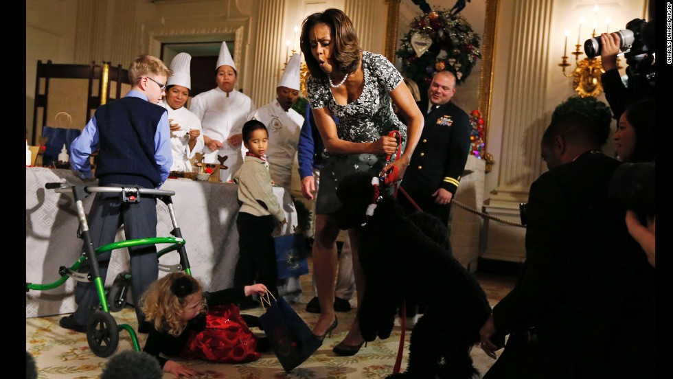 Obama reacts as Ashtyn Gardner, a 2-year-old from Mobile, Alabama, loses her balance while greeting Sunny, one of the Obamas&#39; dogs, at a White House event in December 2014.