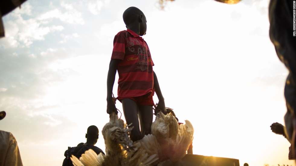 A boy carries chickens off a boat arriving in the village of Minkammen in Awerial county, South Sudan, on Saturday, January 11.