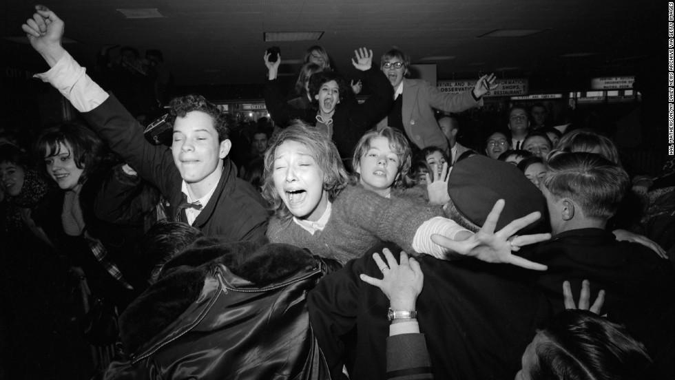 Beatles fans are restrained by police at the airport.