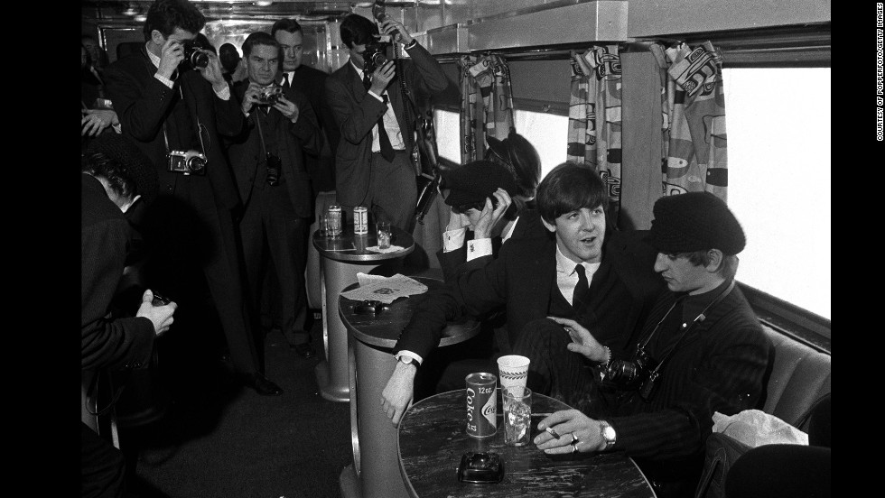 The Beatles have their pictures taken as they sit on a train taking them from New York to Washington on February 11, 1964.