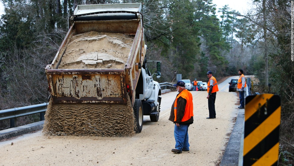 Workers dump sand across a bridge in Covington, Louisiana, on January 27.