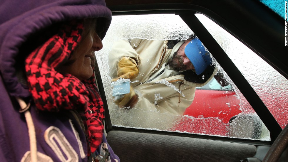 Sue Morrison watches as Chris McAdams scrapes ice from her car on January 29 in Panama City Beach, Florida.