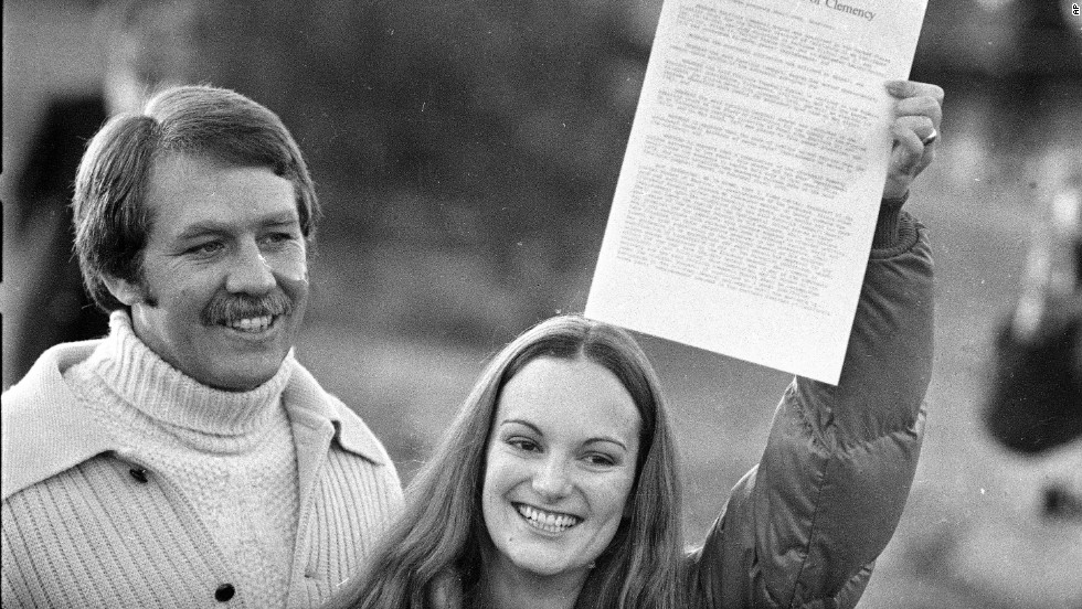 Hearst holds up the executive grant of clemency as she leaves prison on February 1, 1979. With her is her fiance and former bodyguard, Bernard Shaw.