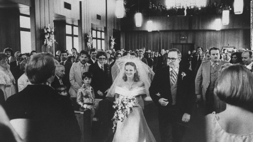 Hearst is walked down the aisle by her father, Randolph Hearst, at the Navy chapel at her wedding to Bernard Shaw in April 1979. 