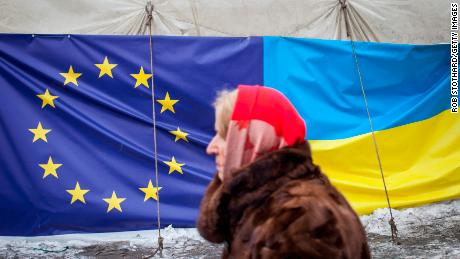 28 जनवरी, 2014 को कीव, यूक्रेन में इंडिपेंडेंस स्क्वायर में यूरोपीय संघ और यूक्रेन के झंडे दिखाते हुए एक महिला एक तंबू से गुजरती है। 