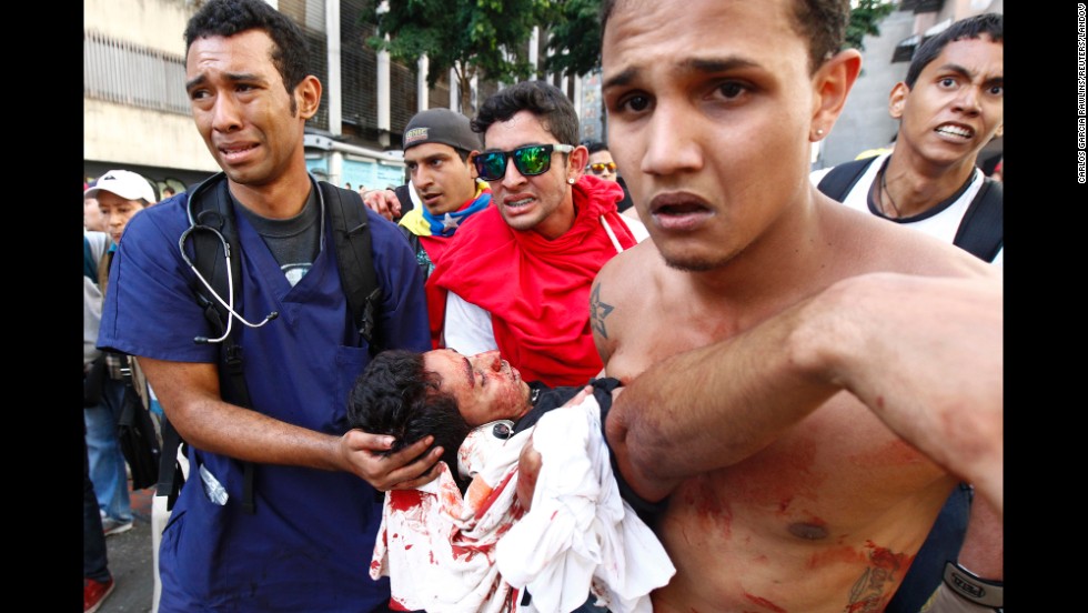 The body of a protester is carried away after gunshots were fired during an anti-government rally in Caracas on February 12.
