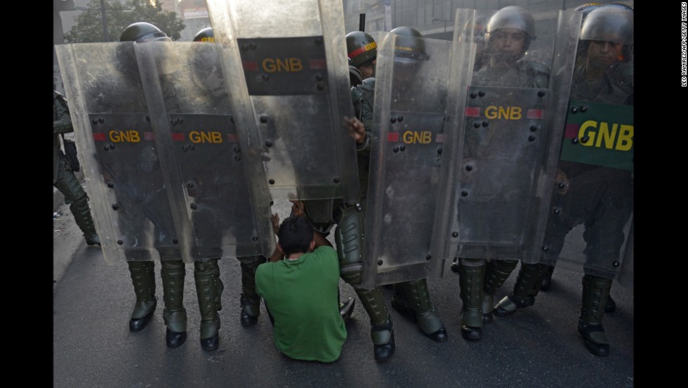 A student falls to the ground in front of riot police in Caracas on February 12.