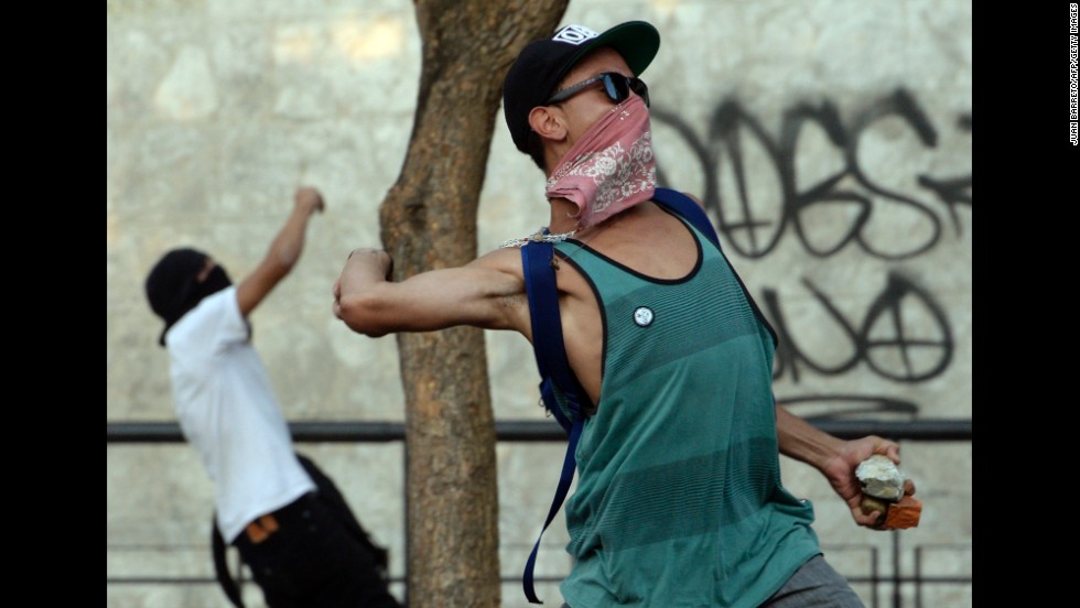 Protesters throw stones at riot police in Caracas on February 19. Protesters have been demanding better security, an end to scarcities, and protected freedom of speech.