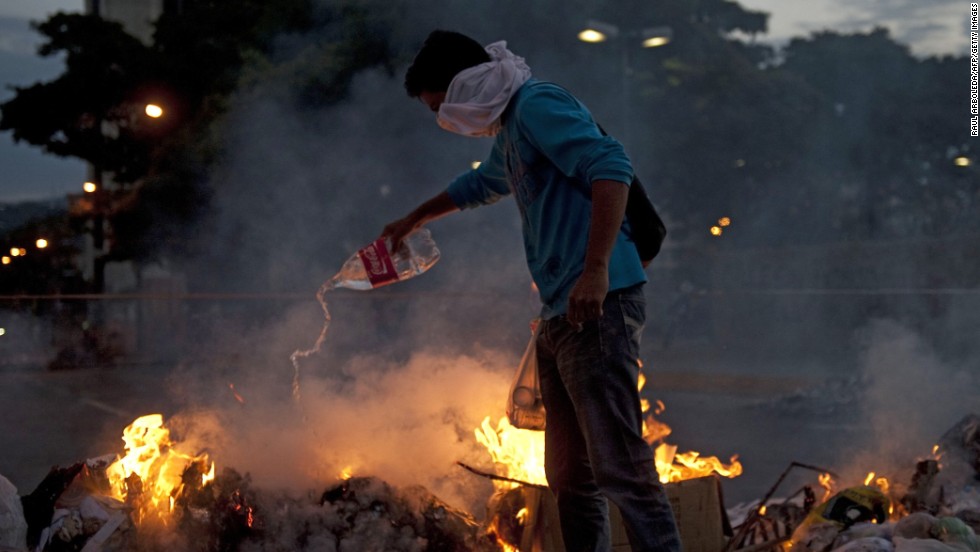A protester adds fuel to a fire during clashes with police in Caracas on February 20.