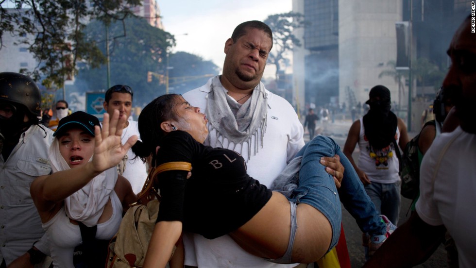 A man carries a woman overcome by tear gas that was fired at anti-government protesters in Caracas on Saturday, February 22. 