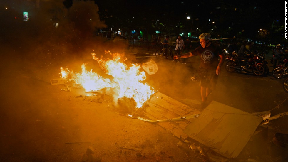 A man stands next to a burning street barricade during a protest against the Venezuelan government in Caracas on Monday, February 24.