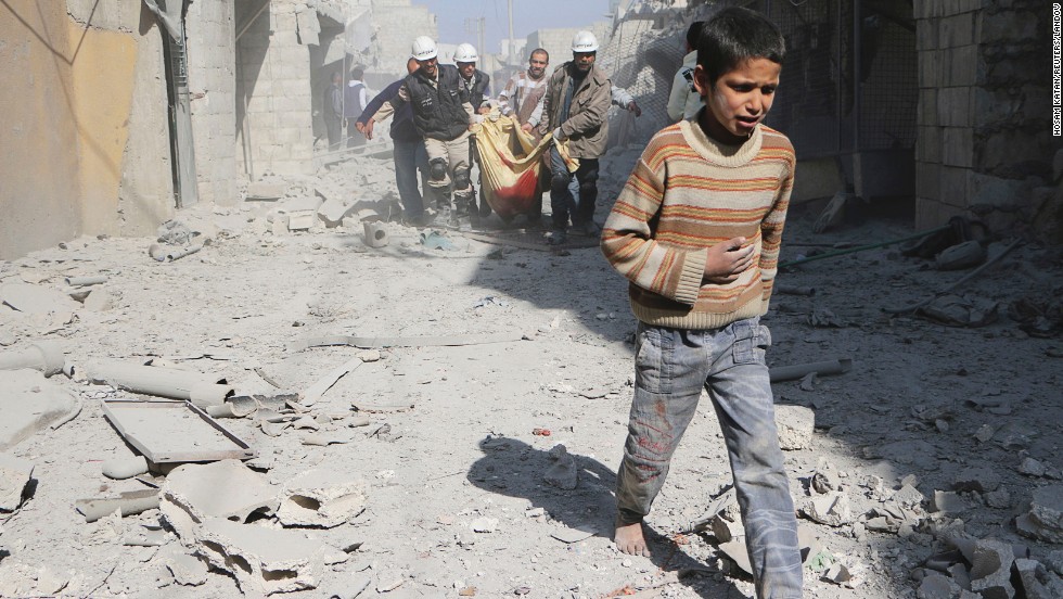 A boy walks ahead of men carrying the body of his mother in Aleppo on Saturday, February 22. According to activists, the woman was killed when explosive barrels were thrown by forces loyal to al-Assad.