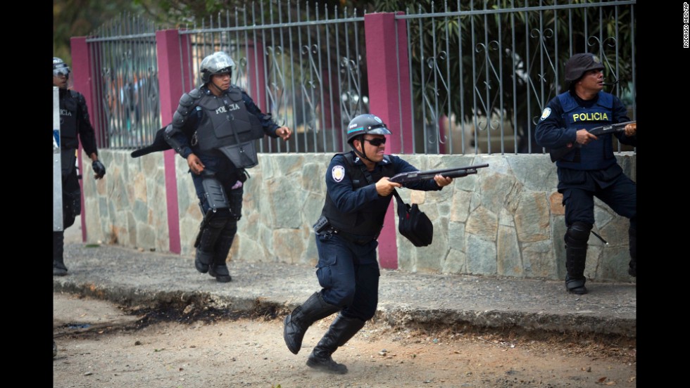 A policeman fires his shotgun to disperse protesters in Valencia on February 26.