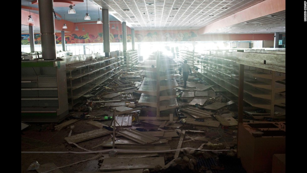 An employee of a supermarket in Maracay, Venezuela, inspects the damage done by looters on February 26.