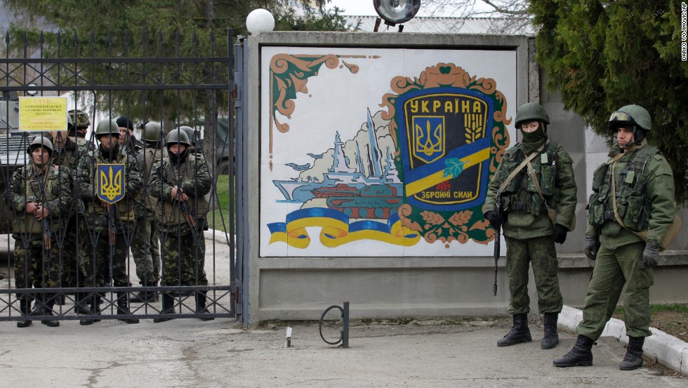 Ukrainian soldiers, left, and unidentified gunmen, right, stand at the gate of an infantry base in Perevalne on March 2. 