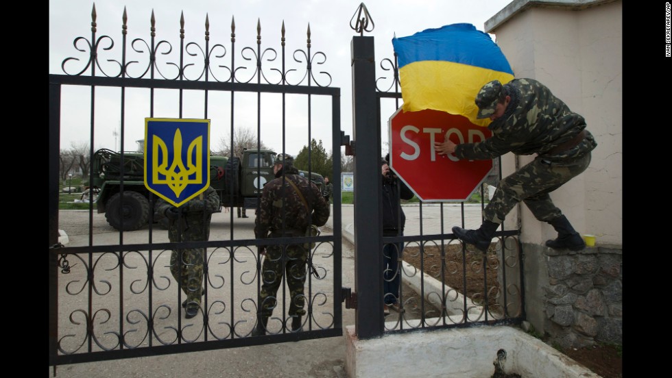 A Ukrainian airman puts the Ukrainian national flag over the gate of the Belbek air base as they guard what&#39;s left under their control on March 4.