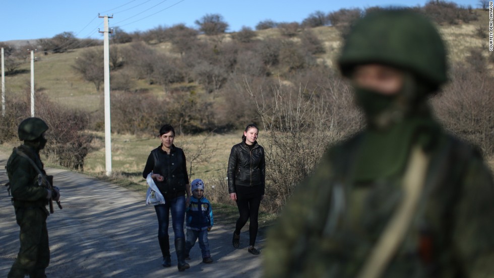 Wives of Ukrainian soldiers walk past Russian soldiers to visit their husbands guarding a military base in Perevalne on March 3.