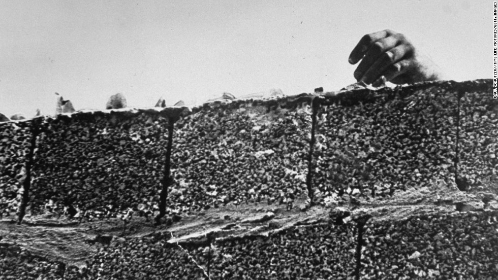 A hand reaches over the glass imbedded in the newly constructed Berlin Wall, which divided the eastern and  western sectors of the city in August 1961. The U.S. had  rejected proposals by Soviet leader Nikita Khrushchev to make Berlin a &quot;free city&quot; with access controlled by East Germany, and on August 15, Communist authorities began construction on the wall to prevent East Germans from fleeing to West Berlin. 