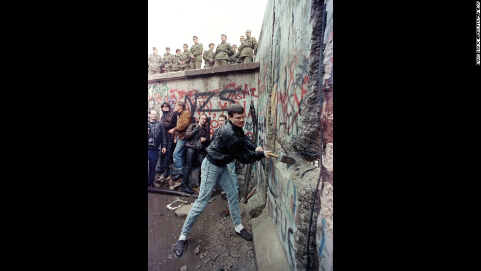 A demonstrator pounds away at the Berlin Wall as East Berlin border guards look on from above the Brandenburg Gate on November 11, 1989. Gorbachev renounced the Brezhnev Doctrine, which pledged to use Soviet force to protect its interests in Eastern Europe. On September 10, Hungary opened its border with Austria, allowing East Germans to flee to the West. After massive public demonstrations in East Germany and Eastern Europe, the Berlin Wall fell on November 9.