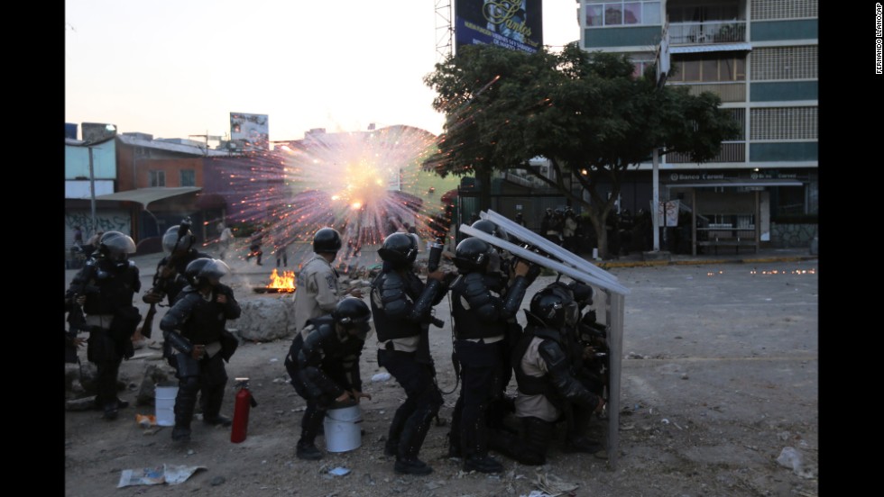 National Guard members take cover as a firecracker launched by protesters explodes nearby in Caracas on Wednesday, March 5.