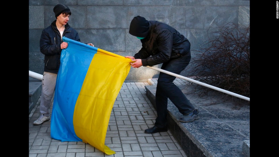 Pro-Russia protesters remove a Ukrainian flag from a flagpole taken from a government building in Donetsk on March 9.