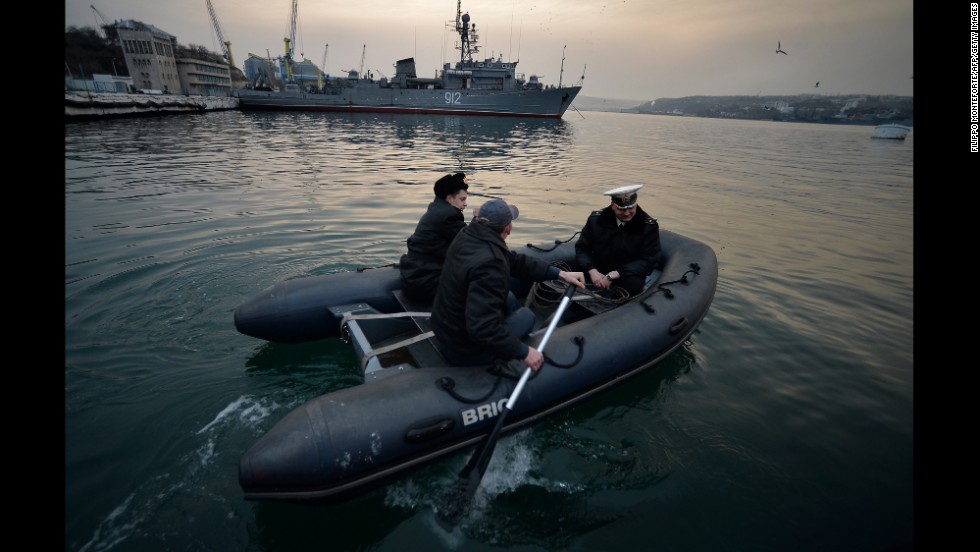 Ukrainian naval officers board a boat in front of the Russian minesweeper Turbinist in Sevastopol&#39;s harbor on March 11.