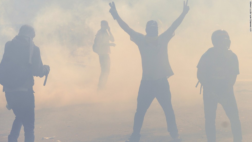 Students walk amid tear gas shot by riot police in Caracas on March 12.