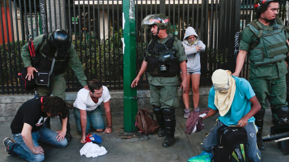 Anti-government protesters kneel as National Guardsmen arrest them in Caracas on March 16.