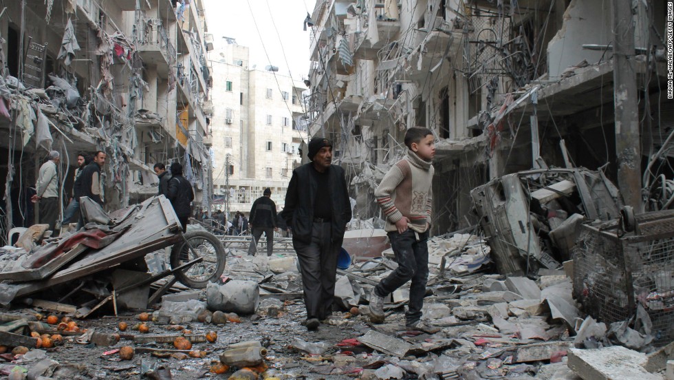 An elderly man and a child walk among debris in a residential block of Aleppo on March 18. 