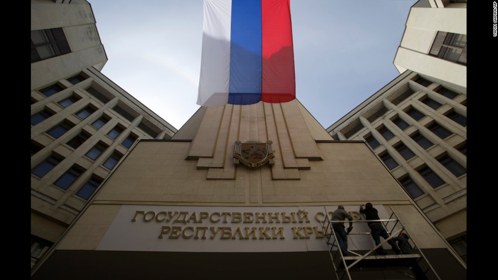 A Russian flag waves as workers install a new sign on a parliament building in Simferopol, Crimea&#39;s capital, on March 19.