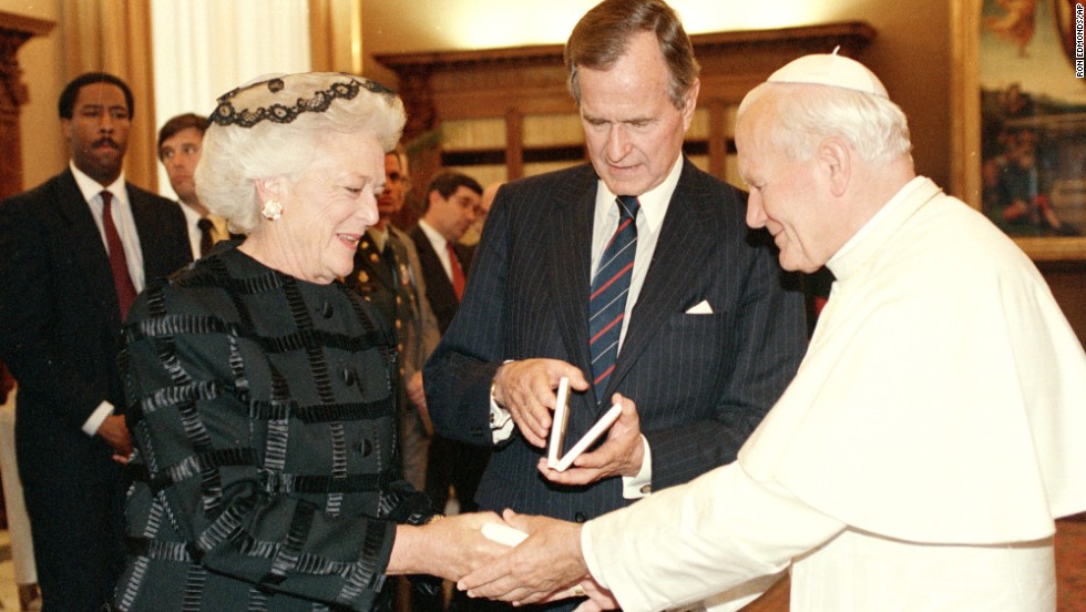 Pope John Paul II presents first lady Barbara Bush with a Vatican Medal as President George H.W. Bush looks at his medal during a ceremony at the Vatican in 1989.