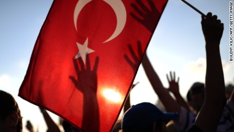 A protester holds up a Turkish flag as others raise their hands during a demonstration in Taksim square in Istanbul on June 8, 2013. Thousands of angry Turks took to the streets on June 8 to join mass anti-government protests, defying Prime Minister Recep Tayyip Erdogan&#39;s call to end the worst civil unrest of his decade-long rule. Erdogan, meanwhile, was meeting in Istanbul with top officials of his Justice and Development Party (AKP) to discuss the crisis, and a deputy prime minister was due to make a speech later on June 8. AFP PHOTO/BULENT KILIC (Photo credit should read BULENT KILIC/AFP/Getty Images)