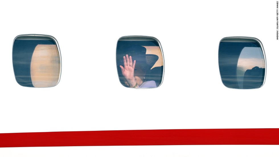 The Queen waves goodbye through an airplane window at Ciampino airport.