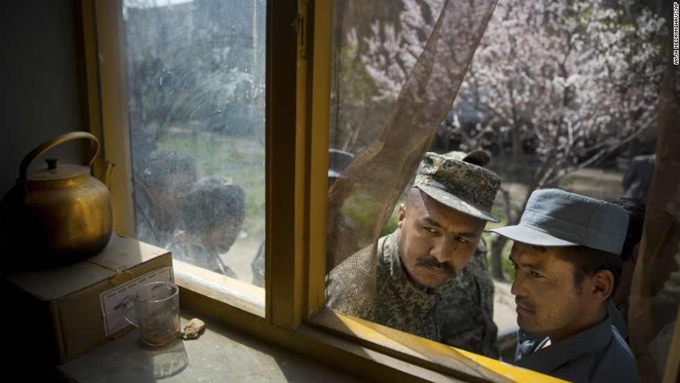 An Afghan soldier, left, and a policeman peek through a window of a school in Kabul, Afghanistan, as they line up with others to get their voter registration card on Tuesday, April 1.