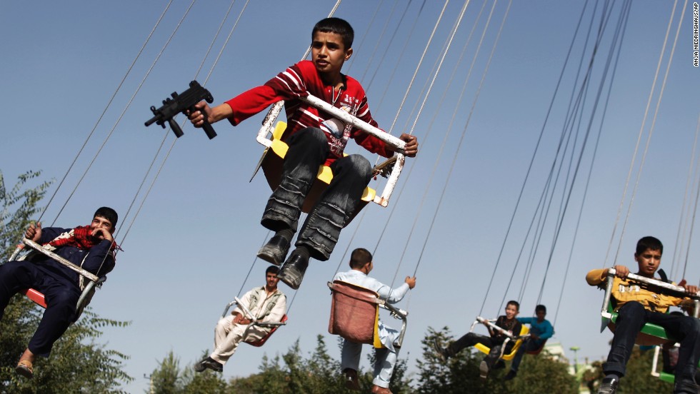 An Afghan boy holds a toy gun as he rides a merry-go-round in Kabul in September 2009.