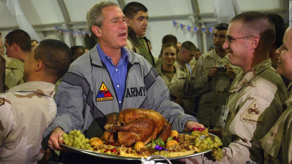 U.S. President George W. Bush carries a platter of Thanksgiving turkey and fixings as he visits U.S. troops in Baghdad in November 2003.
