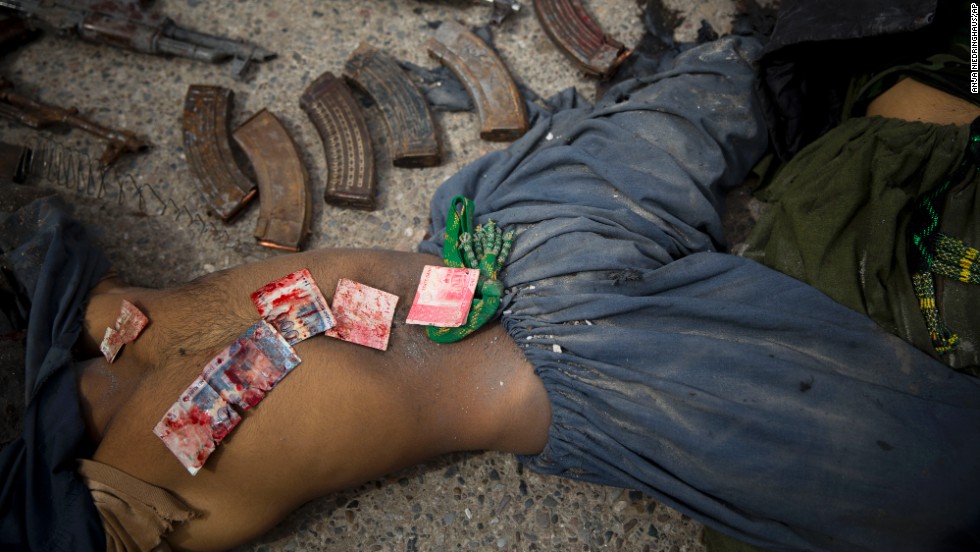 Following an attack Wednesday, March 12, on the former Afghan intelligence headquarters in Kandahar, Pakistani bank notes are displayed on the body of a dead suicide bomber after police found them in his pocket.