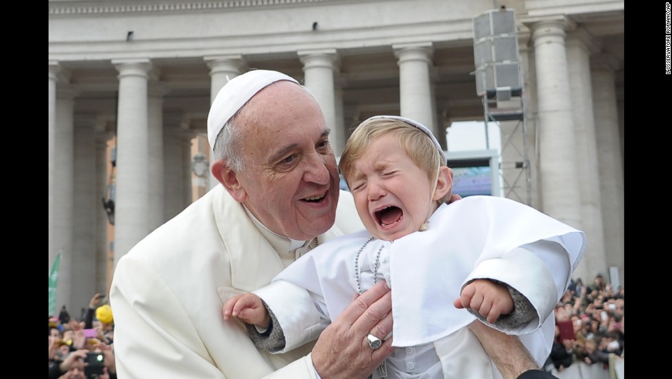 Daniele De Sanctis, a 19-month-old dressed as the pope, is handed to Francis as the pontiff is driven through the crowd in St. Peter&#39;s Square in February 2014.