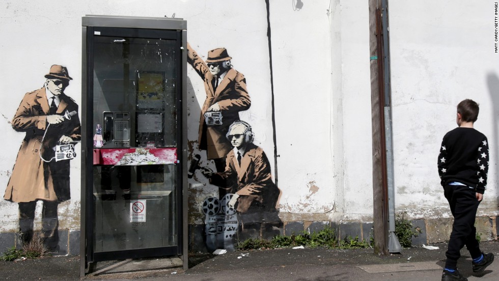 A boy walks past graffiti street art believed to be by Banksy in April 2014. The image depicts men in trench coats and dark glasses holding old-fashioned listening equipment -- apparently a commentary on government surveillance. The artwork appeared on the side of a house in Cheltenham near the Government Communications Headquarters, the UK equivalent of the National Security Agency. 