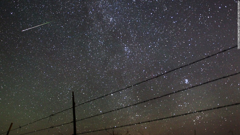 A meteor streaks past the faint band of the Milky Way galaxy above the Wyoming countryside during the 2013 Perseid meteor shower. The show happens each summer when Earth rotates through debris from the Swift-Tuttle comet. 