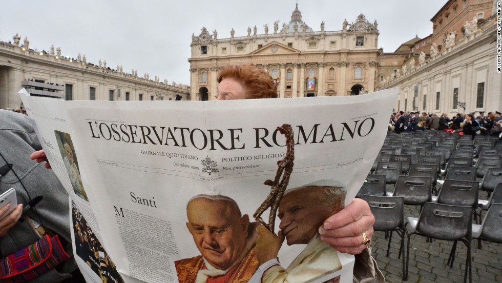 A woman reads a newspaper before the start of the canonization Mass on April 27.