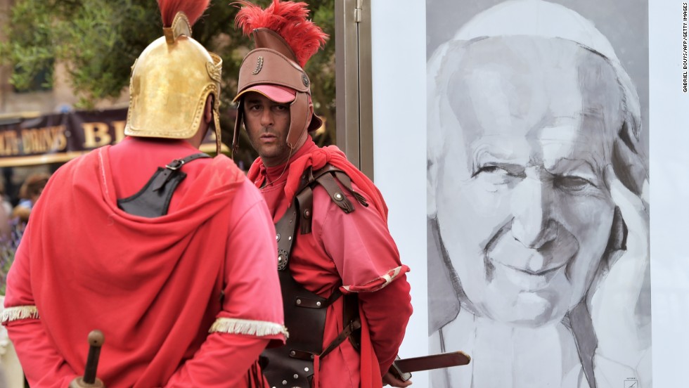 Men dressed as centurions stand by a portrait of Pope John Paul II in Rome during the canonization Mass on April 27.