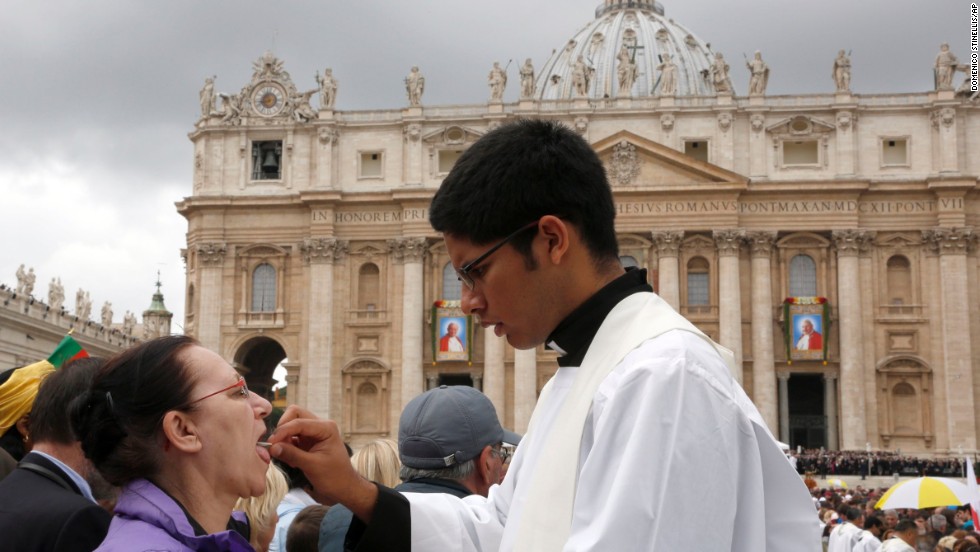 A priest gives Holy Communion to a woman in St. Peter&#39;s Square at the Vatican on April 27.