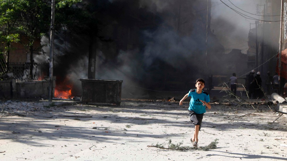 A boy runs in Aleppo on Sunday, April 27, after what activists said were explosive barrels thrown by forces loyal to al-Assad.