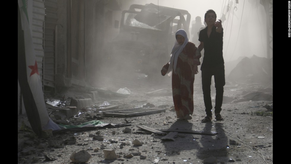 A man helps a woman through debris after reported airstrikes by government forces on Thursday, May 1, in the Halak neighborhood of Aleppo. 