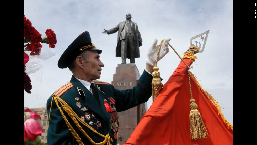 A veteran adjusts a Soviet Army flag in front of a monument of Vladimir Lenin during a Victory Day celebration in Kharkiv, Ukraine.