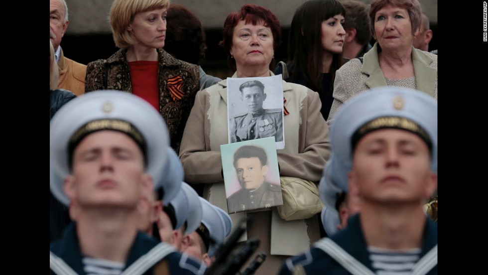At a parade in Sevastopol, Crimea, a woman holds portraits of her relatives who served in the Soviet Army and died during World War II.