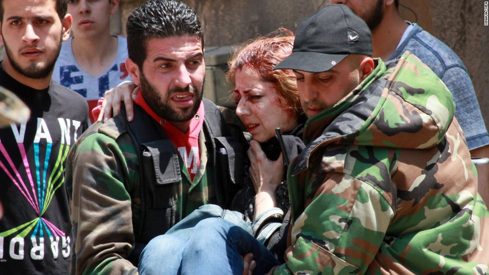 A woman injured when a mine went off is carried in Homs on May 10.