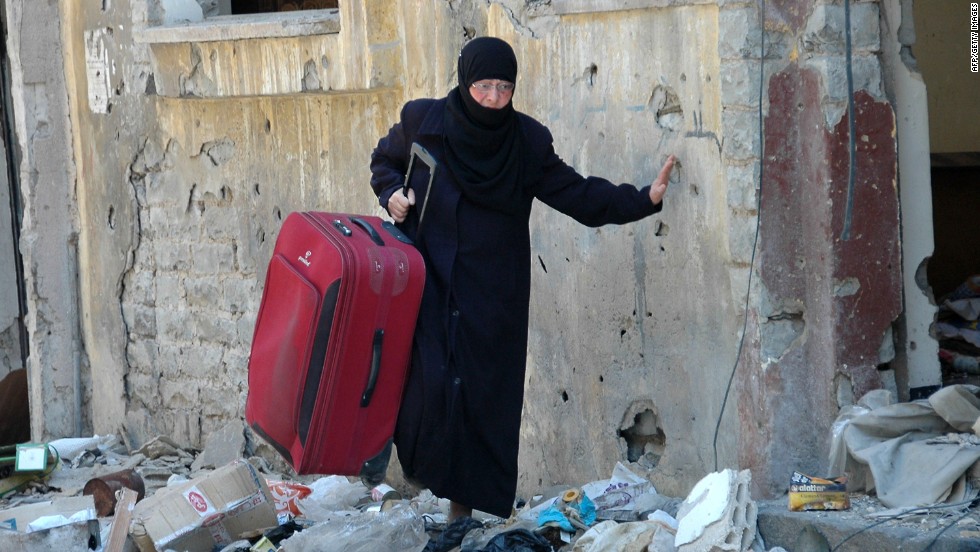 A Syrian woman carries a suitcase along a street in the Juret al-Shayah district of Homs on May 10.